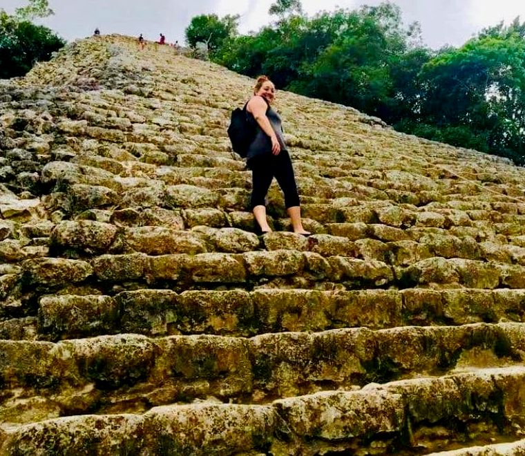 Mulher escalando uma pirâmide maia no sítio arqueológico de Coba, no México