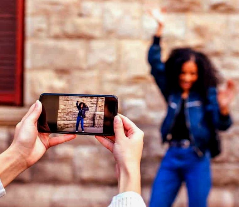 mulher tirando foto de outra mulher em seu celular |  Ansiedade de viajar sozinho
