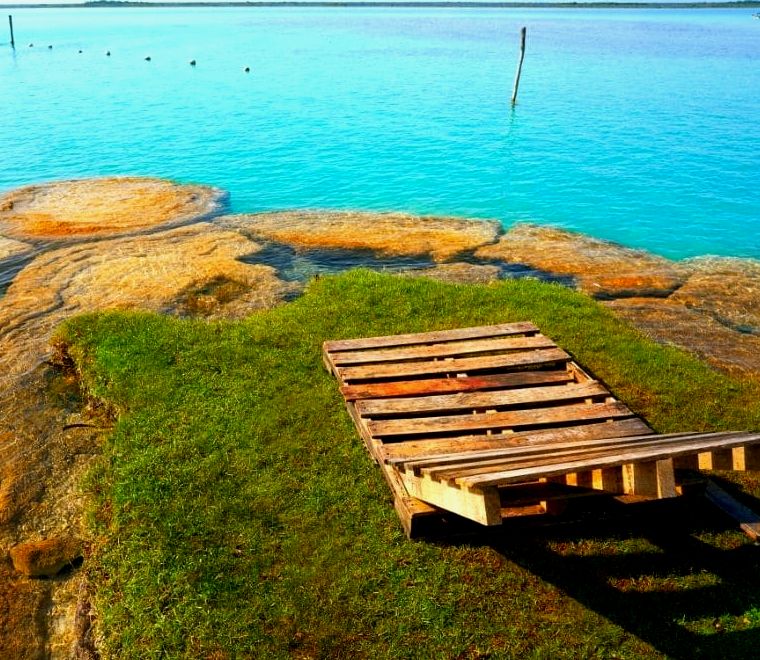 espreguiçadeira perto das águas azuis da lagoa bacalar méxico