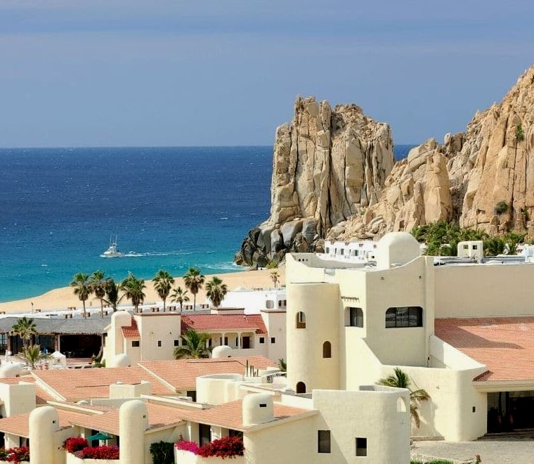 lindas casas brancas com telhados rosa e grandes formações rochosas brancas atrás da praia em Cabo San Lucas, uma das melhores cidades litorâneas mexicanas