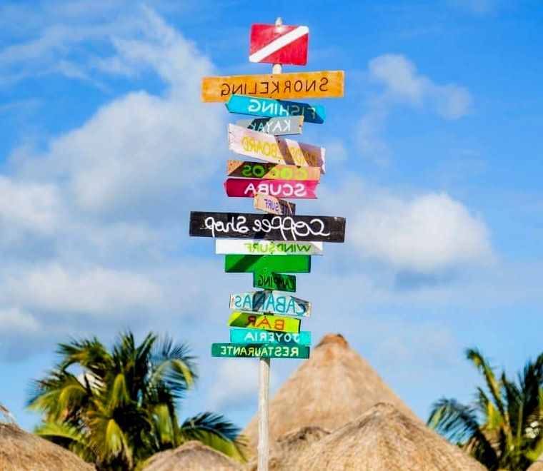 placas de colofrul à beira-mar e cabanas com telhados de palha na praia de Cozumel, uma das melhores cidades litorâneas mexicanas