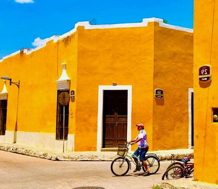 cidade colonial com paredes amarelas e homem de bicicleta na rua - passeios de um dia saindo de Mérida