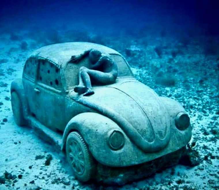 escultura no oceano debaixo d'água de um velho carro VW no museu subaquático de cancún, um dos lugares mais exclusivos para se visitar no México