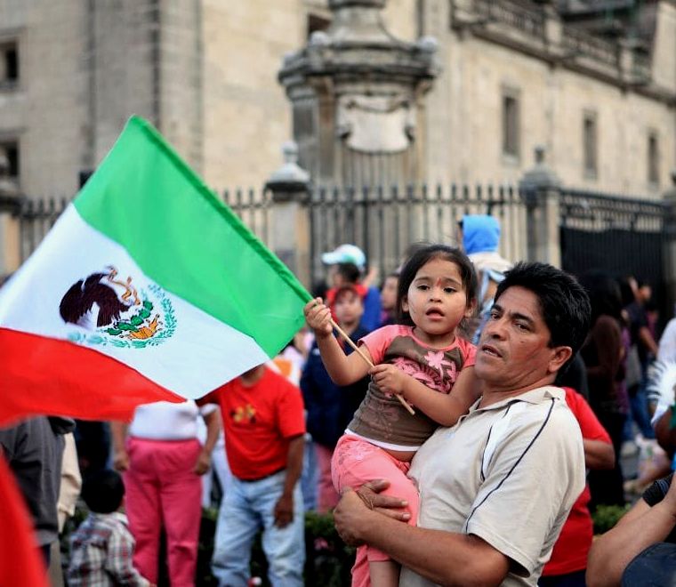 homem mexicano e filha segurando uma bandeira mexicana para os feriados