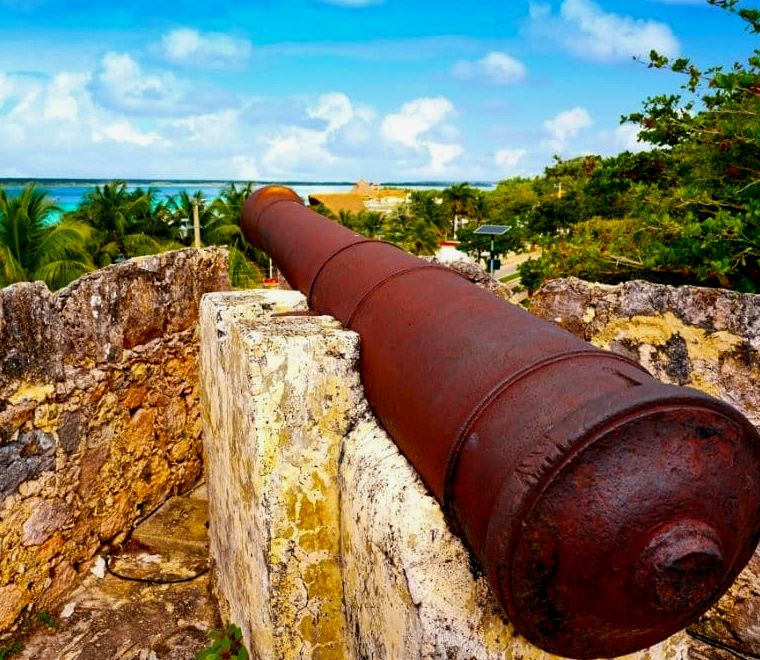 canhão enferrujado em um forte apontado para a praia na lagoa bacalar méxico