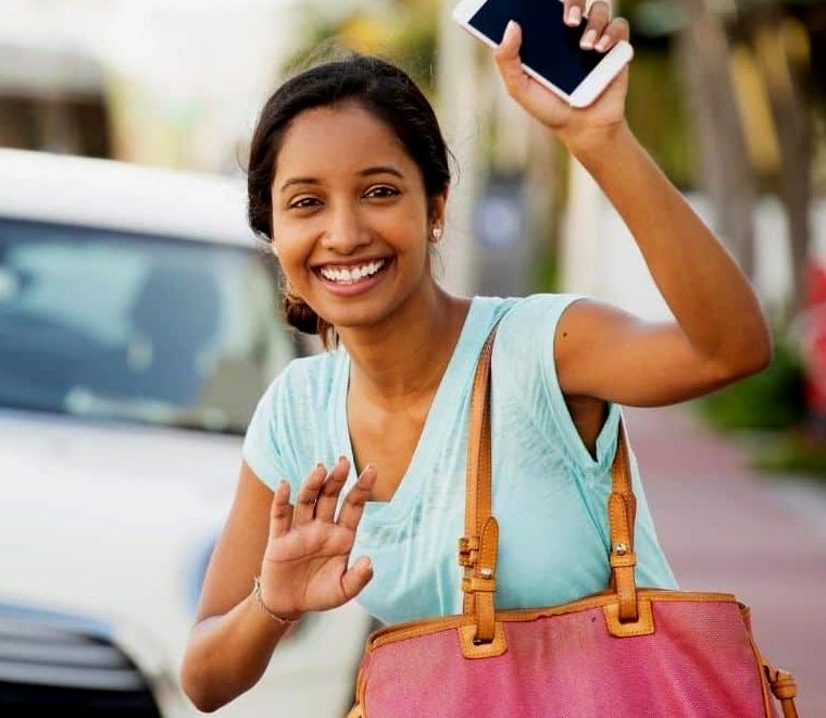 Mulher parada na rua segurando o telefone esperando um Uber