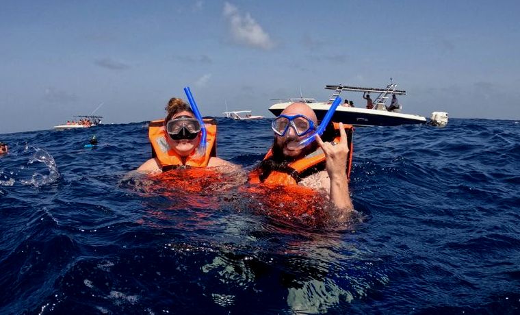 duas pessoas no oceano usando coletes salva-vidas laranja em um passeio de tubarão-baleia em Cancún