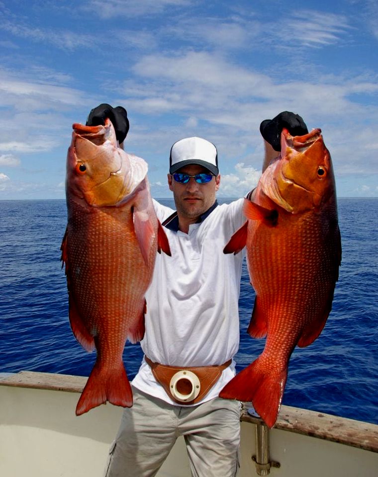homem segurando dois peixes grandes durante um passeio de pesca