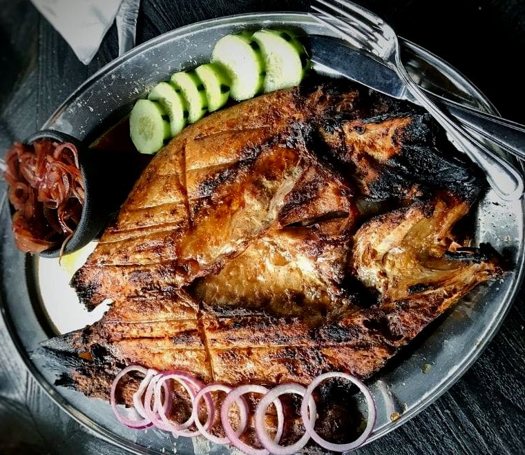 pescado zarandeado em um prato com cebola e pepino ao lado