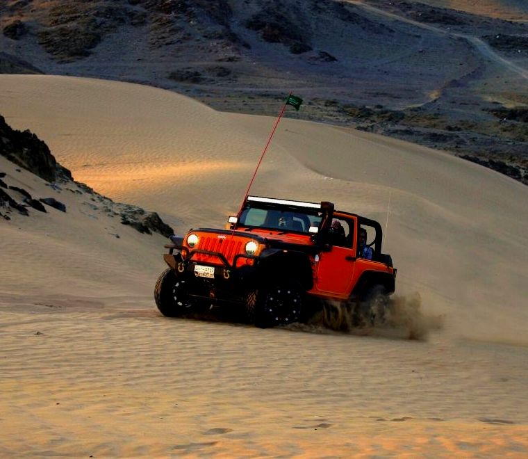 jipe vermelho dirigindo em dunas de areia em cabo san lucas méxico |  alugar um carro em cabo méxico