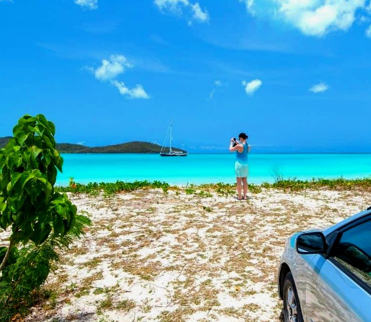 mulher na praia tirando uma foto perto de seu carro alugado no México |  alugar um carro no México
